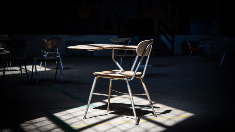 An empty chair in a shadowy classroom